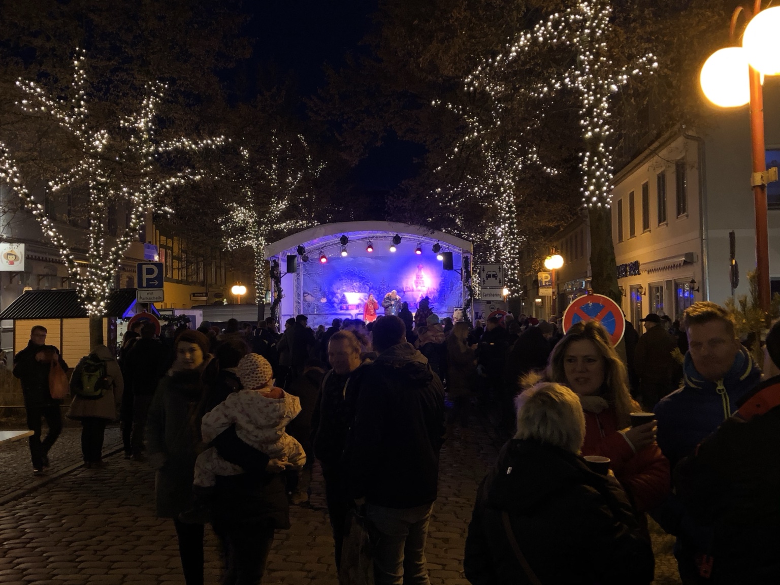 Weihnachtsmarkt mit Bühne, Lichterketten und Publikum